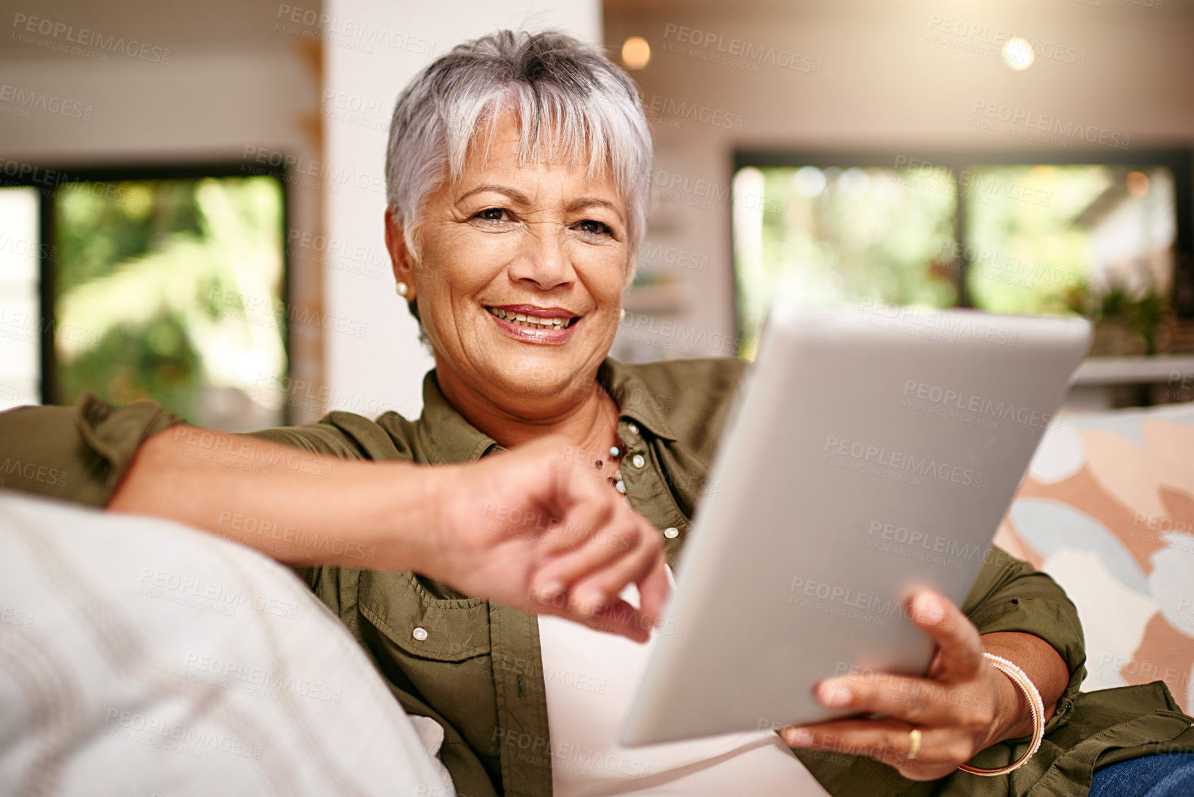 Buy stock photo Portrait of a happy older woman relaxing on the sofa with her digital tablet at home