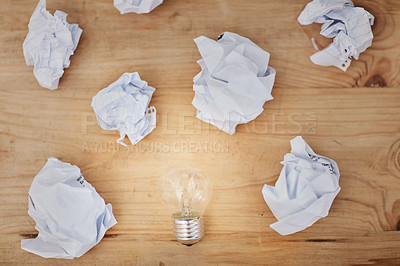 Buy stock photo High angle shot of a lightbulb surrounded by crumpled pieces of paper on a desk