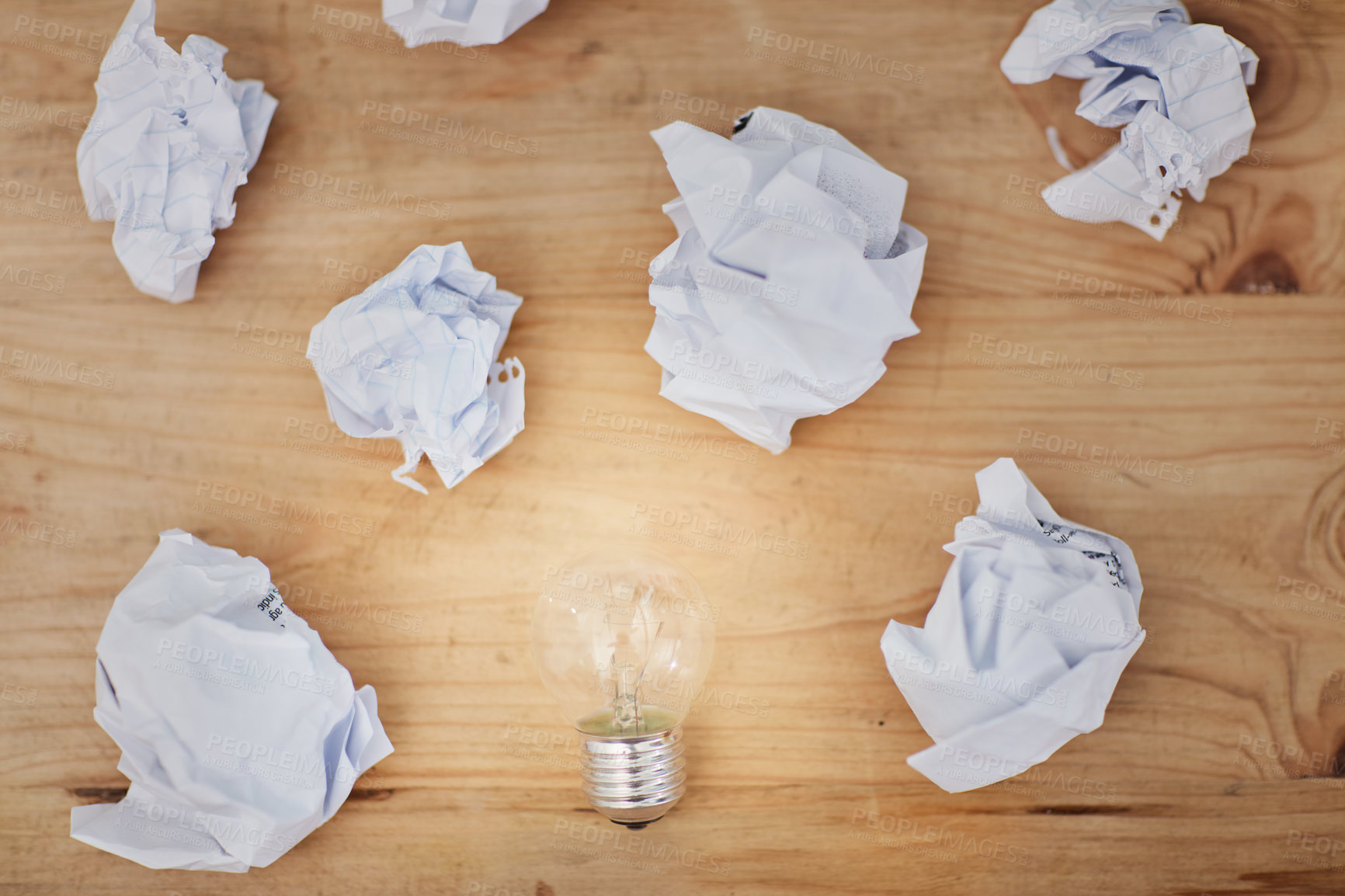 Buy stock photo High angle shot of a lightbulb surrounded by crumpled pieces of paper on a desk