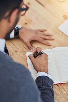 Buy stock photo Closeup shot of a businessman writing in a notebook in an office