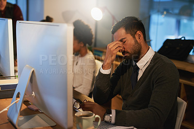 Buy stock photo Shot of a stressed out young businessman working late at the office with his colleagues
