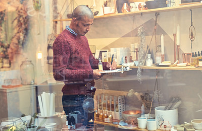 Buy stock photo Shot of a young man checking stock in his store