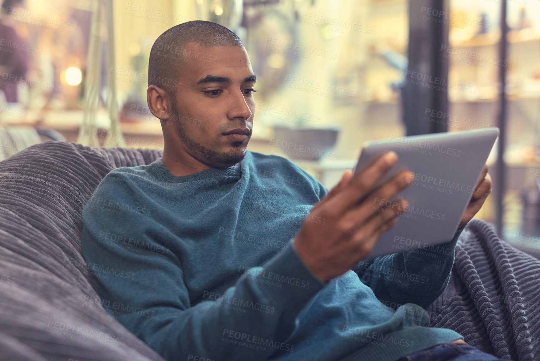 Buy stock photo Man, tablet and relax on bean bag for online, social media and communication with internet or text. African person, technology and chill on foam chair for streaming film, video and games with app