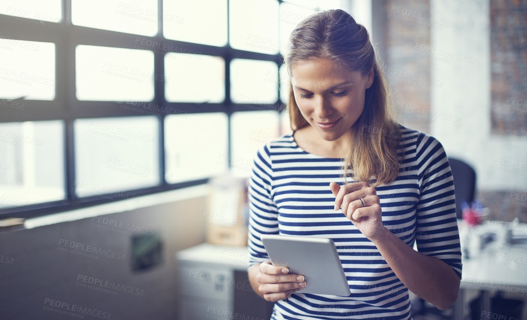 Buy stock photo Shot of a young designer using her digital tablet in her office