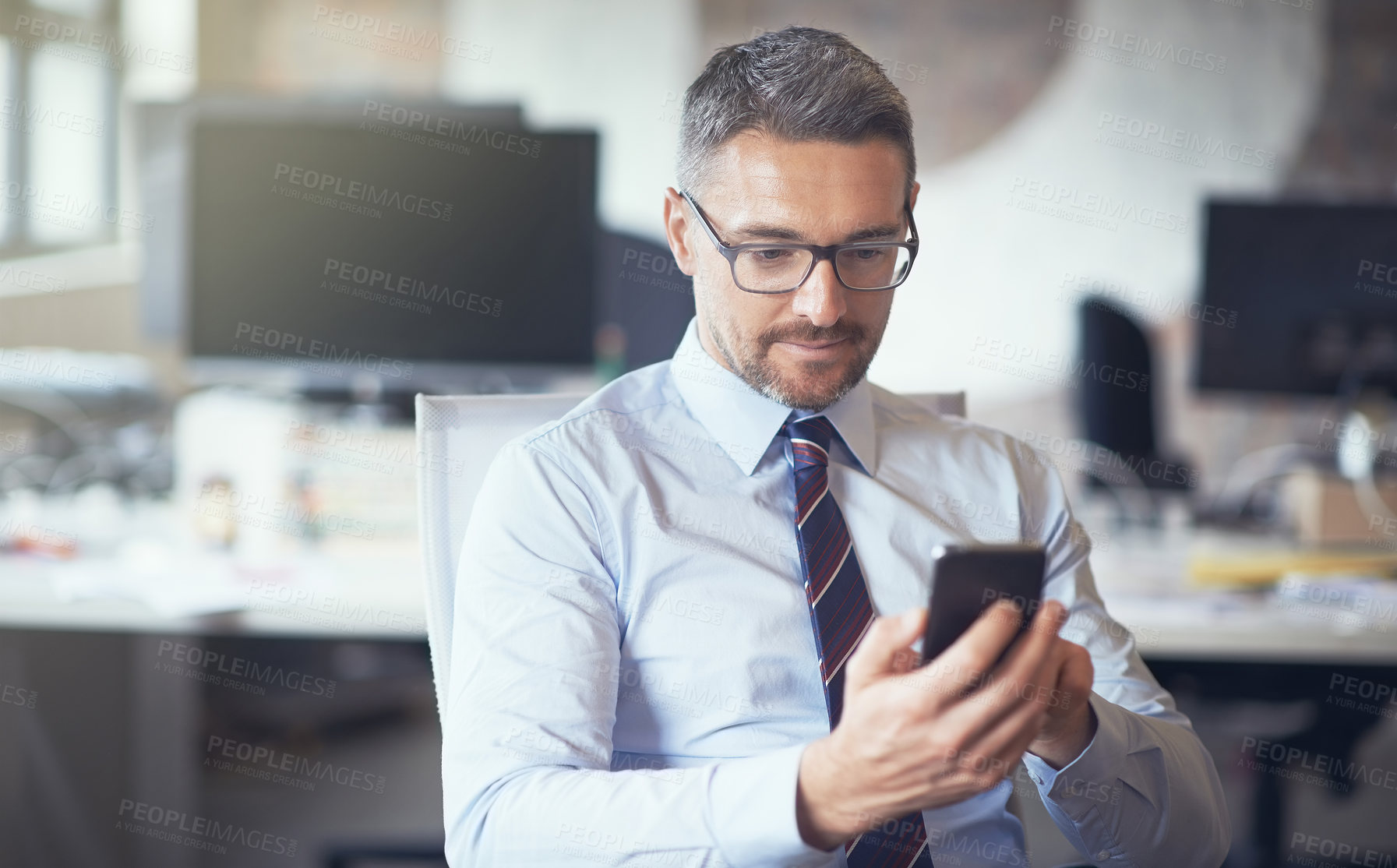 Buy stock photo Cropped shot of a businessman using his cellphone while sitting in his office