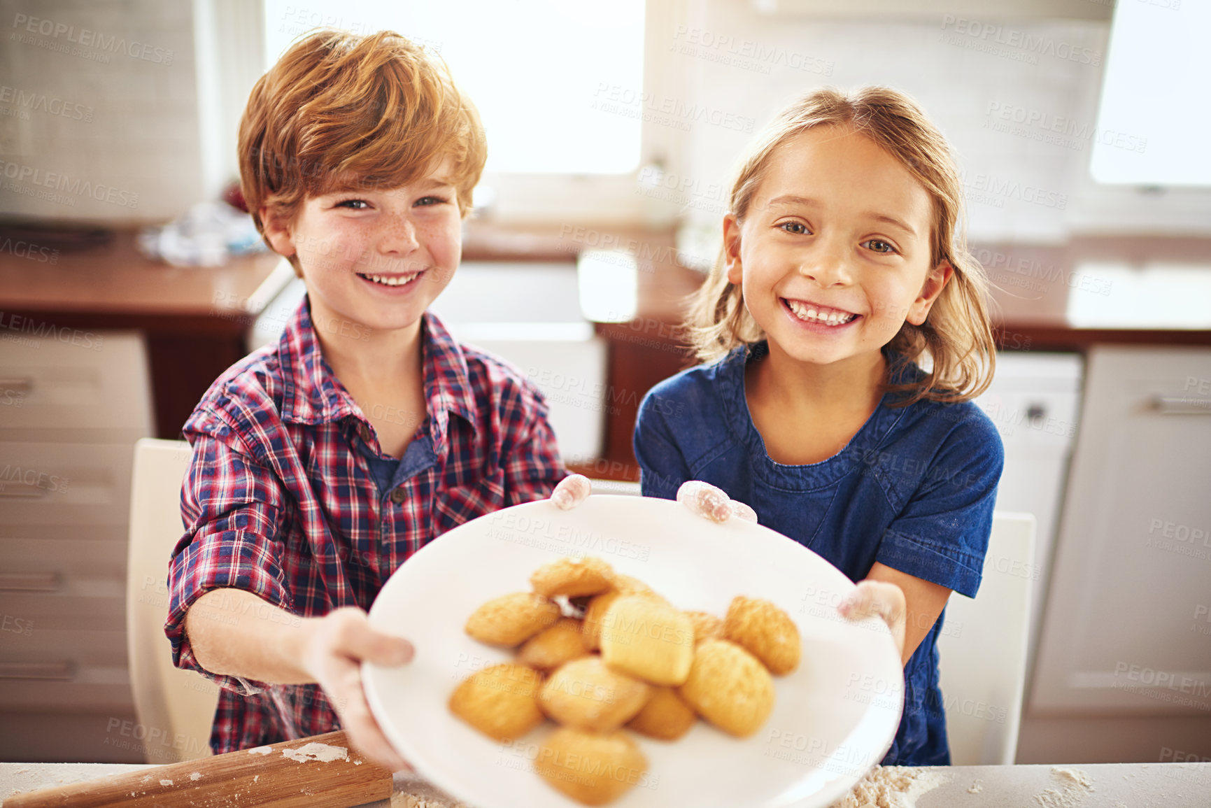 Buy stock photo Portrait of two young children holding a plate of biscuits together