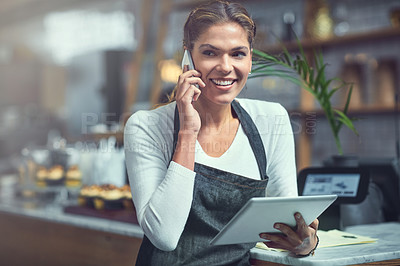Buy stock photo Shot of a young woman using a phone and digital tablet in the store that she works at