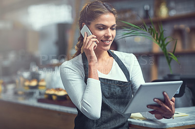 Buy stock photo Shot of a young woman using a phone and digital tablet in the store that she works at