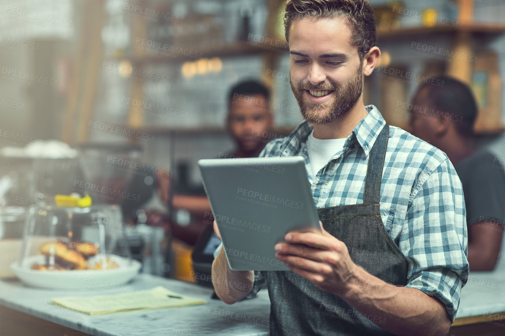 Buy stock photo Shot of a young man using a digital tablet in the store that he works at