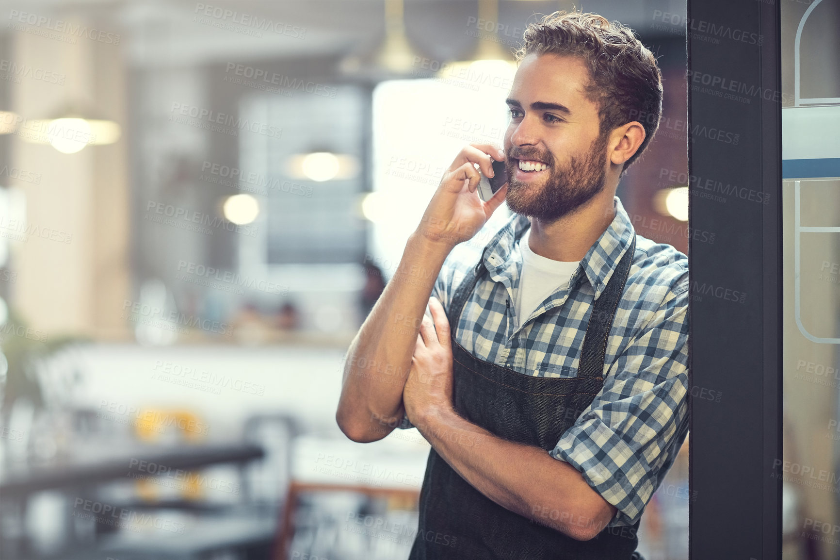 Buy stock photo Happy man, waiter or door with phone call at cafe for small business, reservation or conversation. Young, male person or owner with smile on mobile smartphone for chat or booking at indoor restaurant