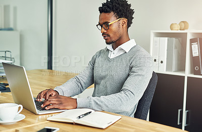 Buy stock photo Cropped shot of a young businessman working on a laptop in a modern office
