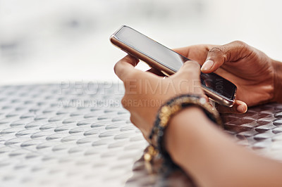 Buy stock photo Cropped shot of an unidentifiable woman using a smartphone at a table