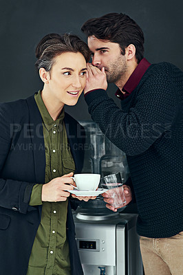 Buy stock photo Cropped shot of two colleagues gossiping by the water cooler during a coffee break
