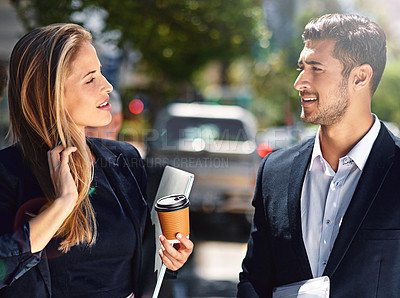 Buy stock photo Shot of two corporate colleagues having a discussion while walking down the street