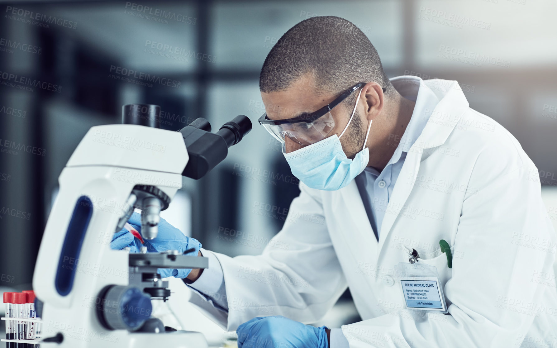 Buy stock photo Serious young male scientist working on scientific cure for covid in a lab. Professional man in science at work during pandemic on a medical mission, thinking and vision for a vaccine for the virus.