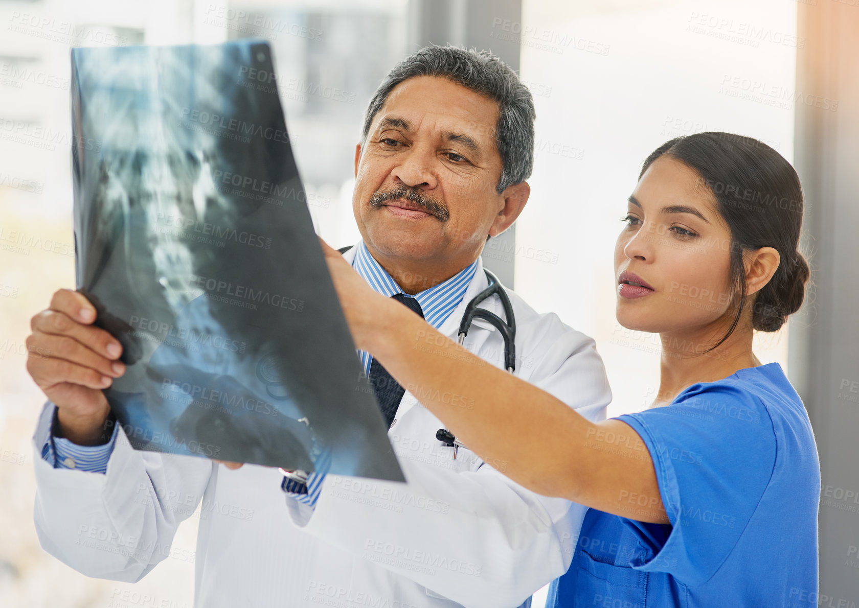 Buy stock photo Shot of a mature doctor and young nurse looking at an x ray together