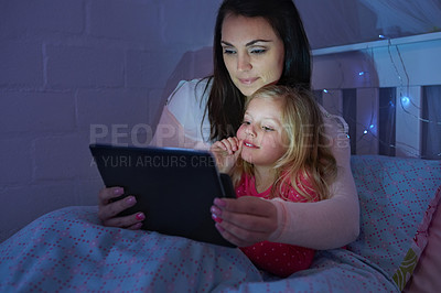 Buy stock photo Shot of a mother and daughter sitting in a bed reading a bedtime story on a digital tablet