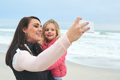 Buy stock photo Cropped shot of a mother and her young daughter taking a selfie on the beach