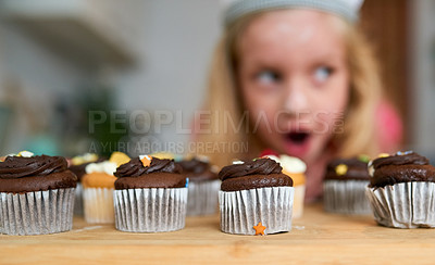 Buy stock photo Shot of a surprised little girl looking at cupcakes she baked at home
