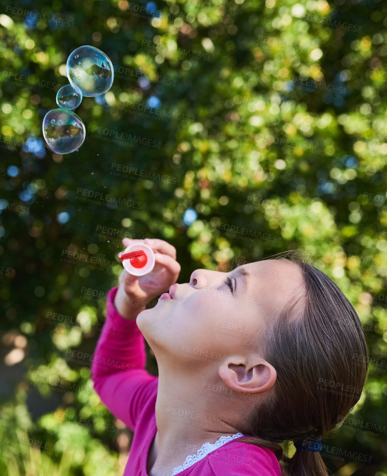 Buy stock photo Shot of a cute young girl blowing bubbles outside