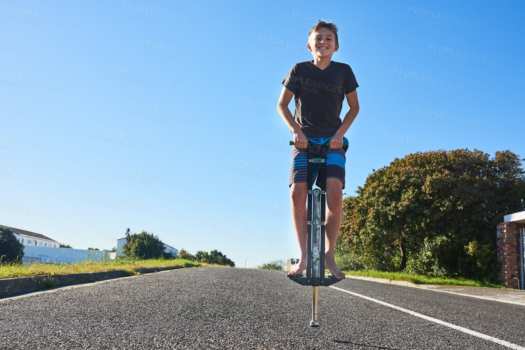 Buy stock photo Full length portrait of a young boy bouncing on a pogo stick outside