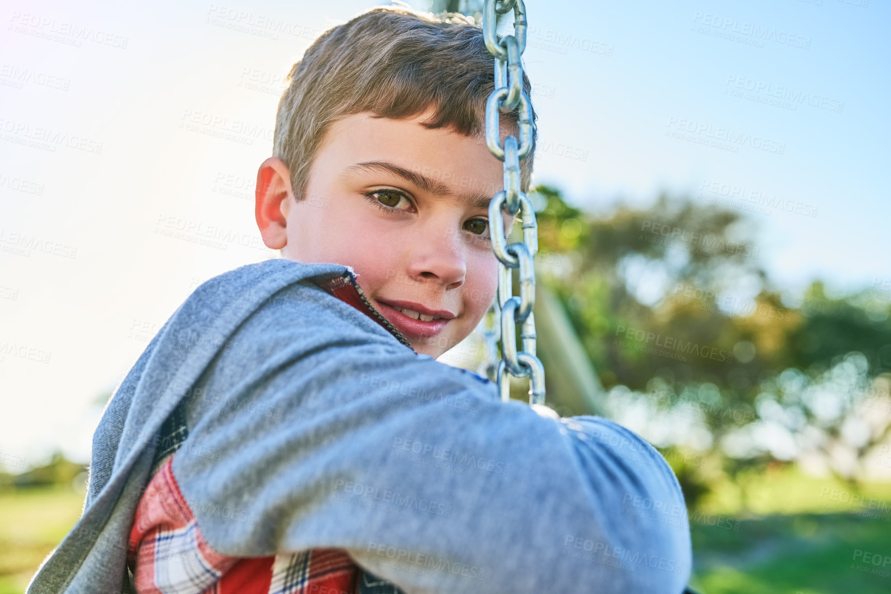 Buy stock photo Portrait of a young boy sitting on a swing in a park