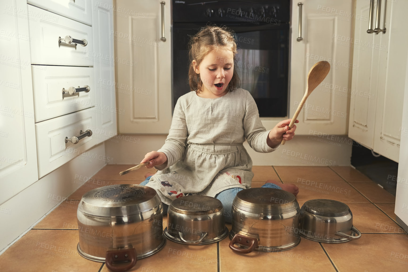 Buy stock photo Shot of a little girl playing drums on a set of pots in the kitchen