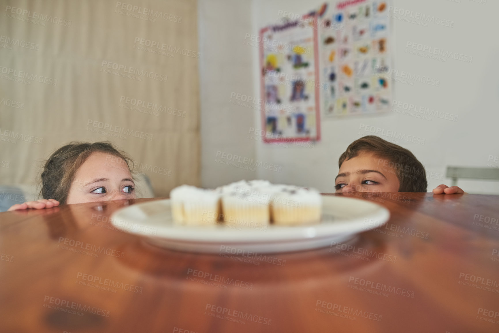 Buy stock photo Cropped shot of two naughty children eyeing a plate of cupcakes