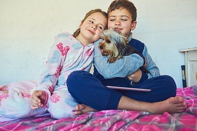Buy stock photo Shot of two young siblings bonding with their pet dog at home