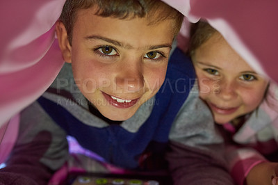 Buy stock photo Portrait of two young siblings lying down under a blanket at home