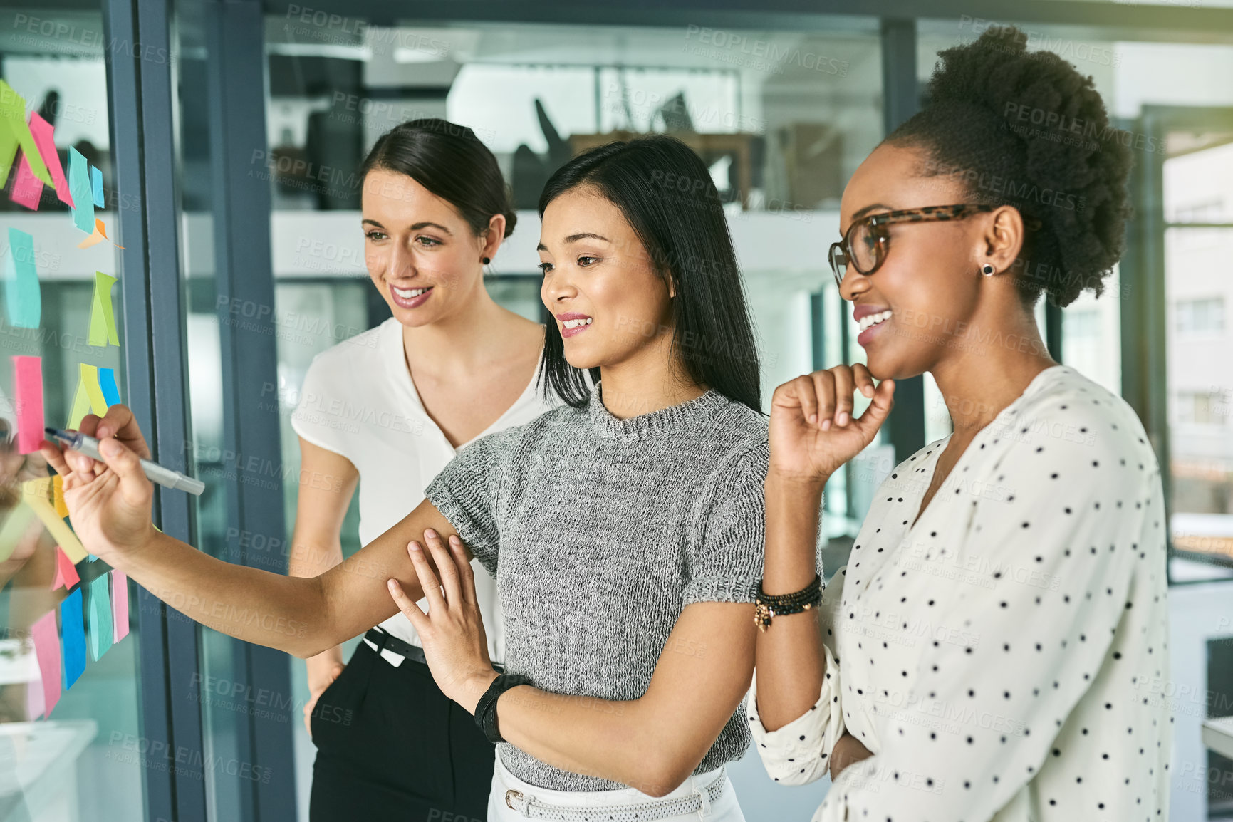 Buy stock photo Business women, smile in meeting or writing schedule on glass wall for brainstorming, teamwork and tasks. Employees, happy and sticky note on clear board for project plan, collaboration or idea