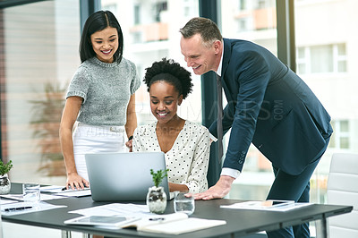 Buy stock photo Cropped shot of three businesspeople gathered around a laptop in the office