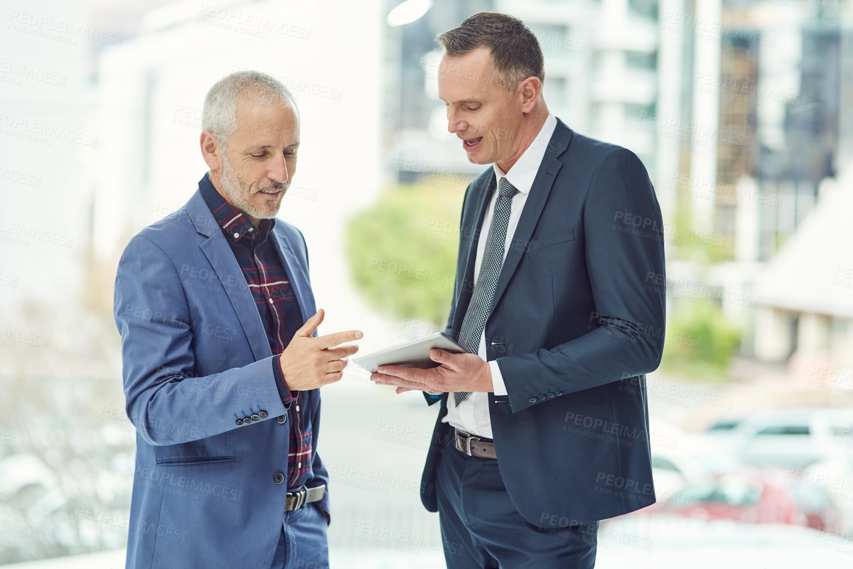 Buy stock photo Cropped shot of two businessmen working on a digital tablet together in a modern office