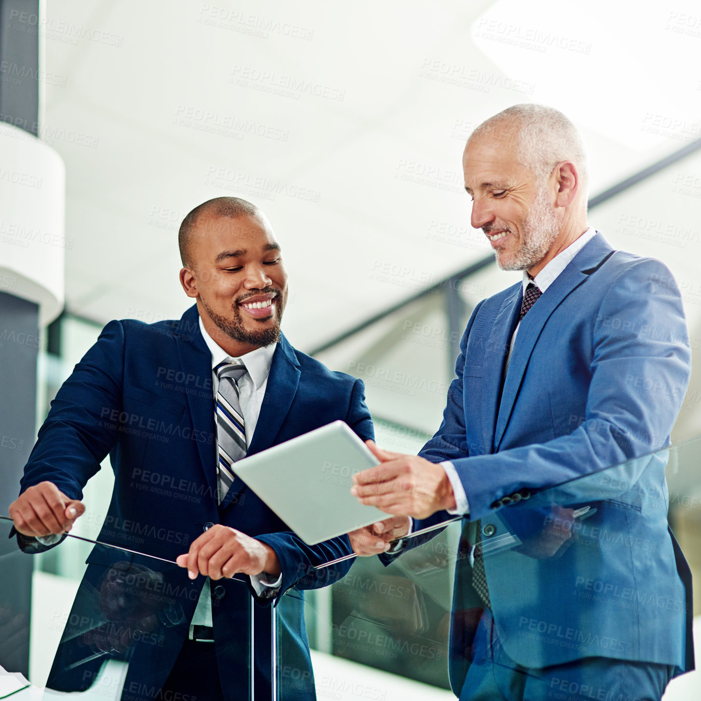 Buy stock photo Cropped shot of a businessman showing something to his colleague on his tablet in the office