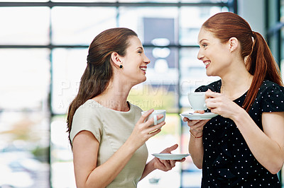 Buy stock photo Cropped shot of two businesswomen standing and chatting during a coffee break