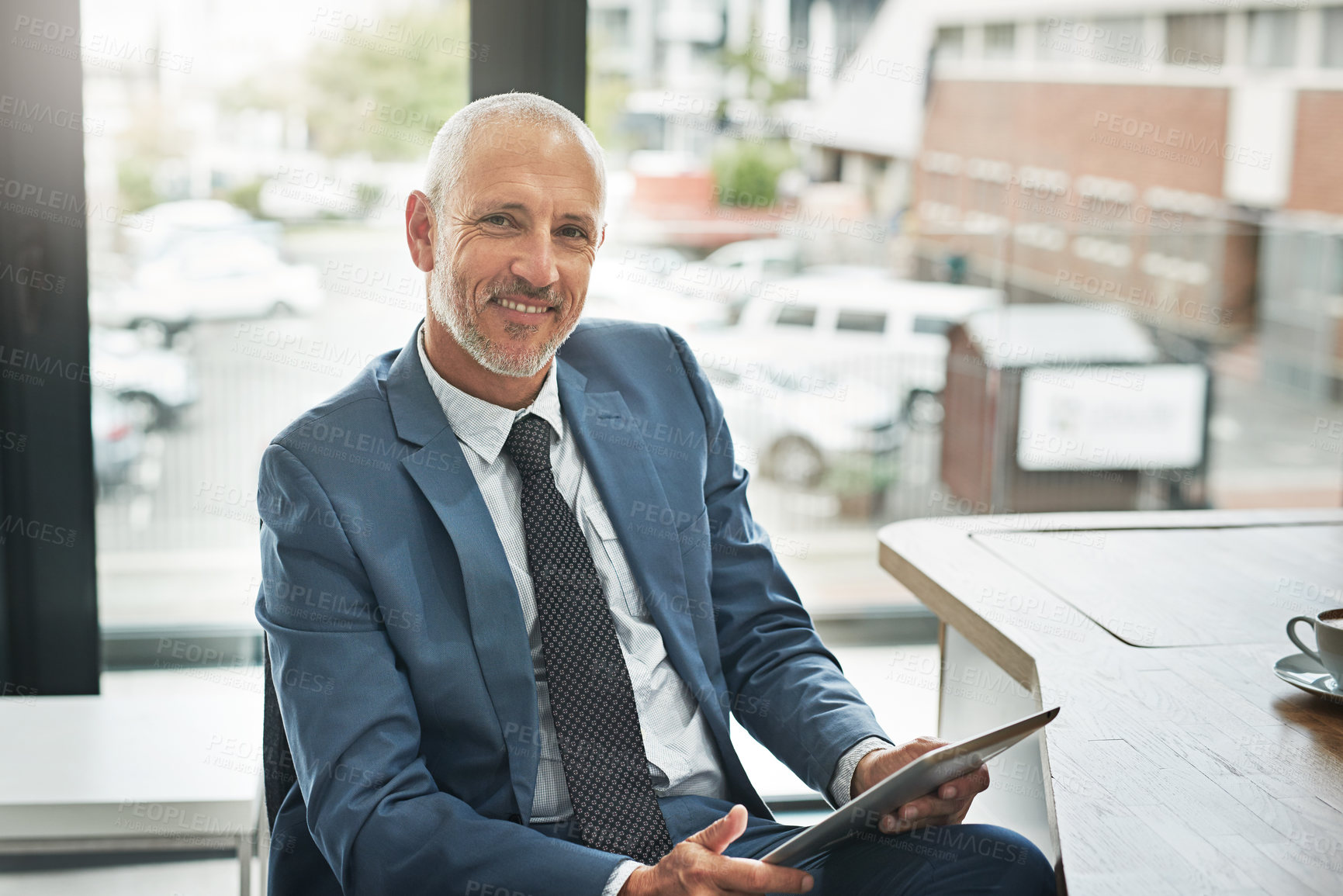 Buy stock photo Portrait of a mature businessman working on a digital tablet in a modern office