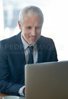 Buy stock photo Cropped shot of a mature businessman working on a laptop in a modern office