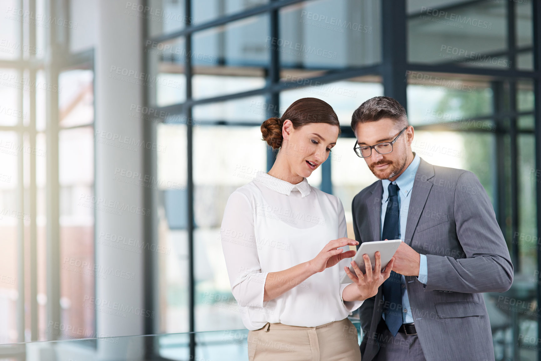 Buy stock photo Cropped shot of two businesspeople looking over a digital tablet in the office