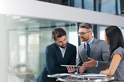 Buy stock photo Cropped shot of a group of businesspeople looking over a digital tablet in the office