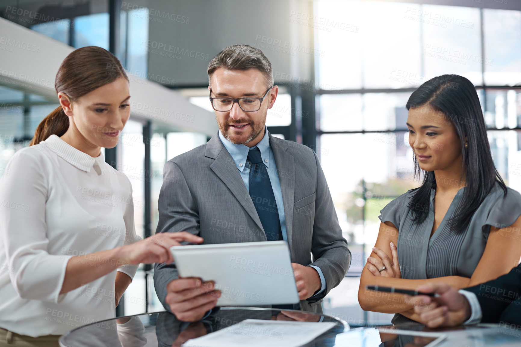 Buy stock photo Cropped shot of a group of businesspeople looking over a digital tablet in the office