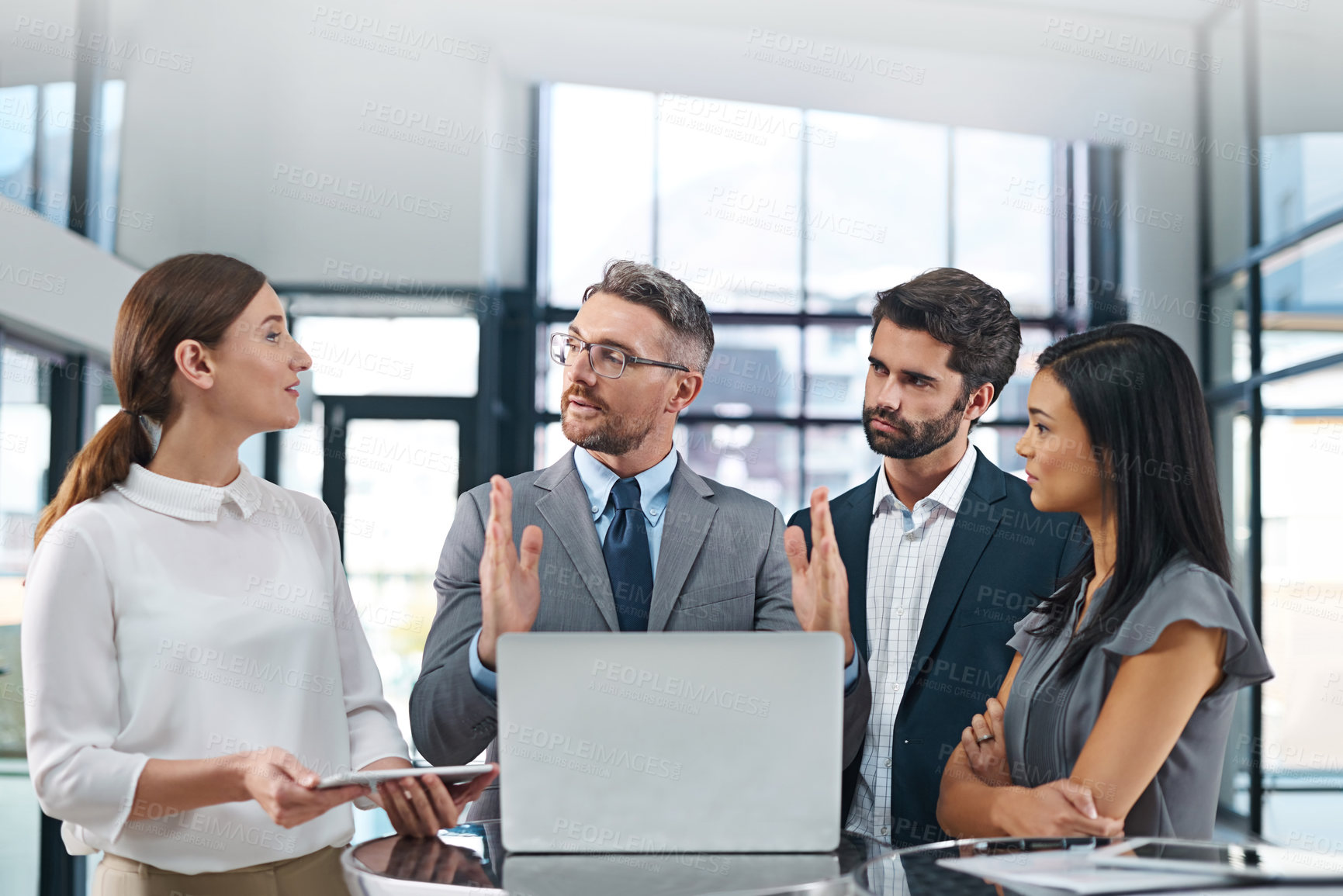 Buy stock photo Cropped shot of a group of businesspeople gathered around a laptop in the office