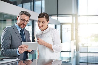 Buy stock photo Cropped shot of two businesspeople looking over a digital tablet in the office
