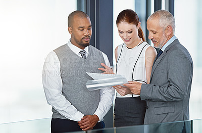 Buy stock photo Cropped shot of a group of businesspeople looking through some paperwork together in an office