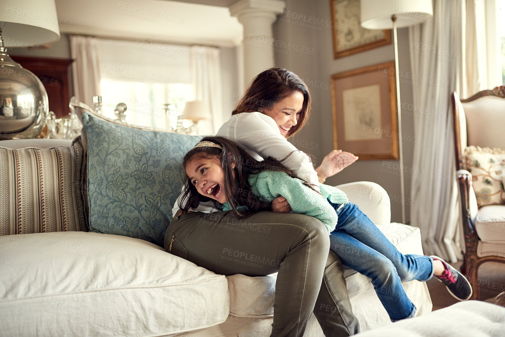 Buy stock photo Shot of a mother and daughter having fun on the sofa at home
