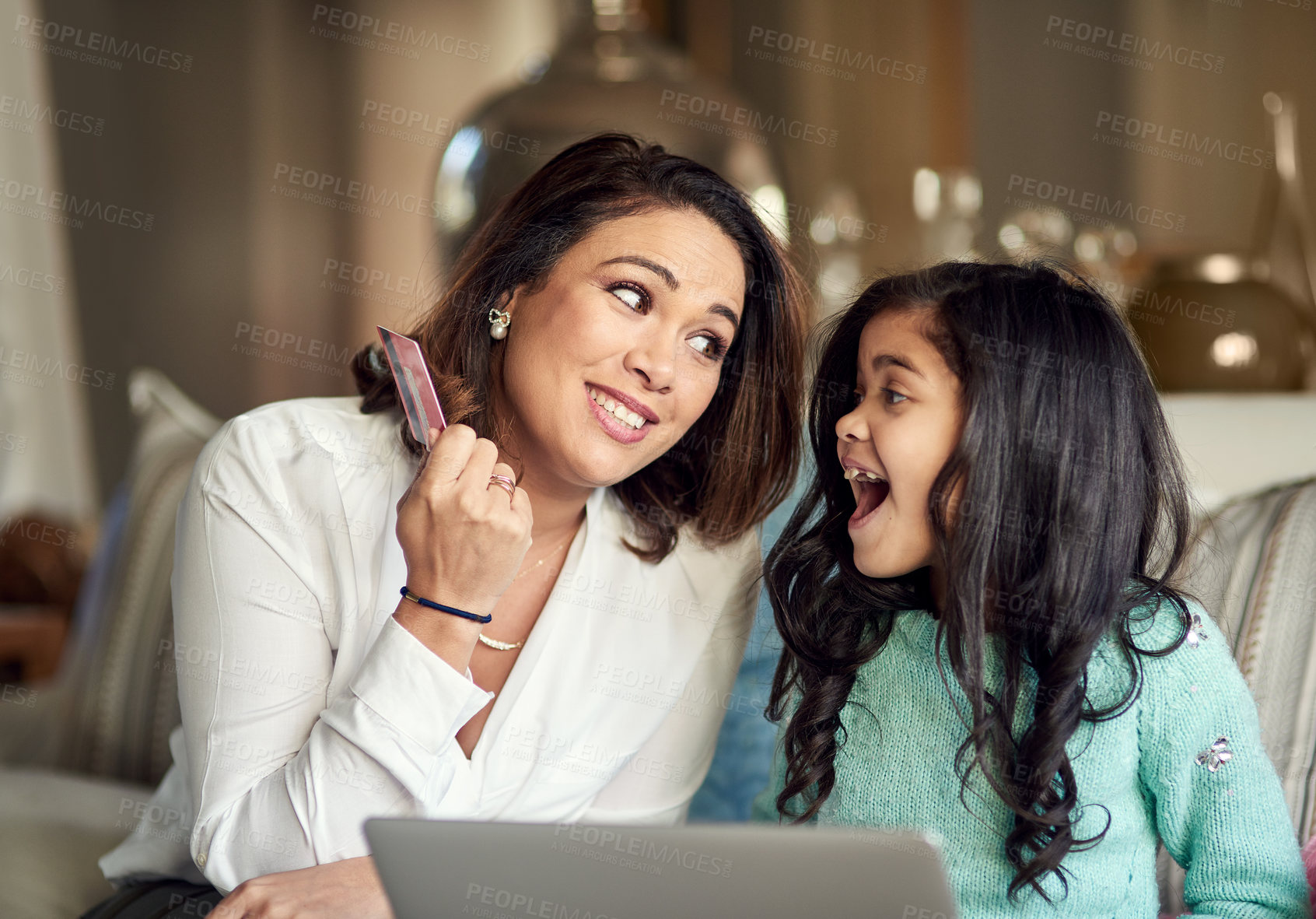 Buy stock photo Shot of a mother using a credit card to buy something for her daughter online