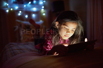 Buy stock photo Shot of a little girl using a digital tablet late at night in her bedroom