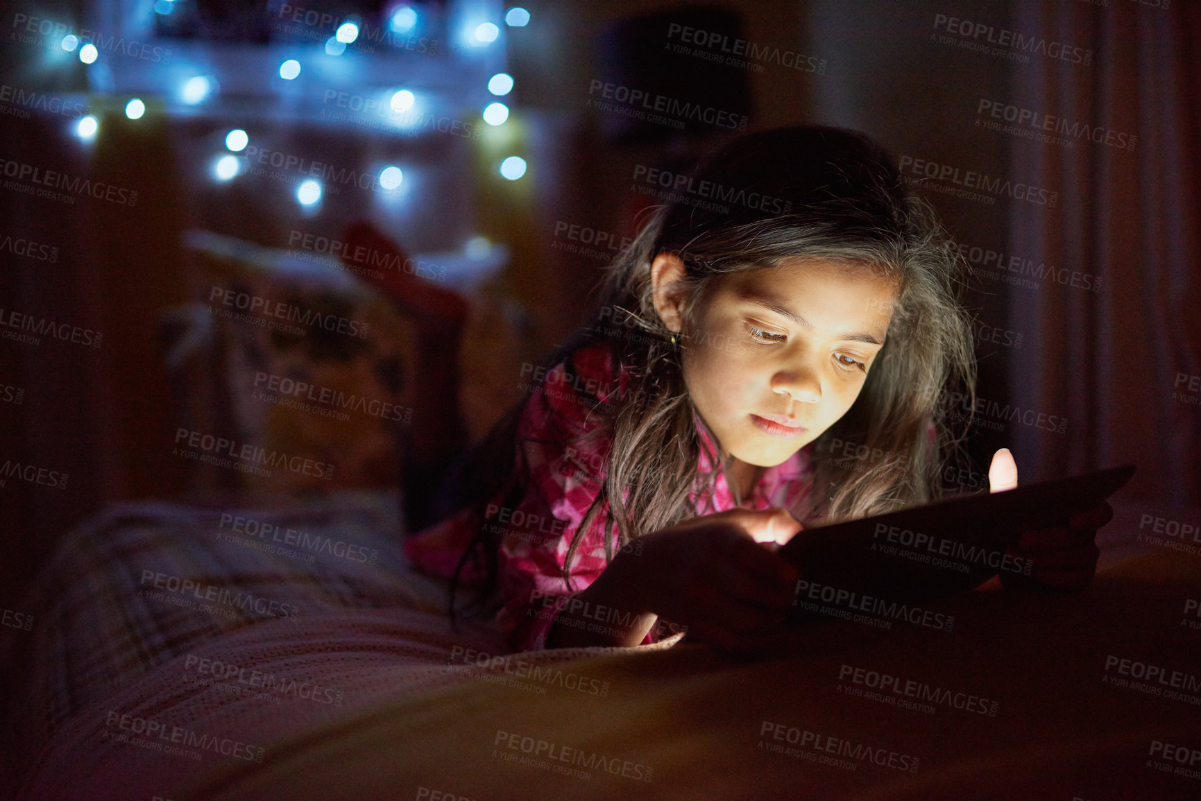 Buy stock photo Shot of a little girl using a digital tablet late at night in her bedroom