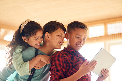 Buy stock photo Shot of young children using a digital tablet together at home