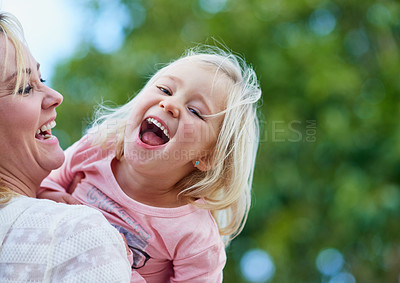 Buy stock photo Shot of a cute little girl laughing while being held by her mother outside