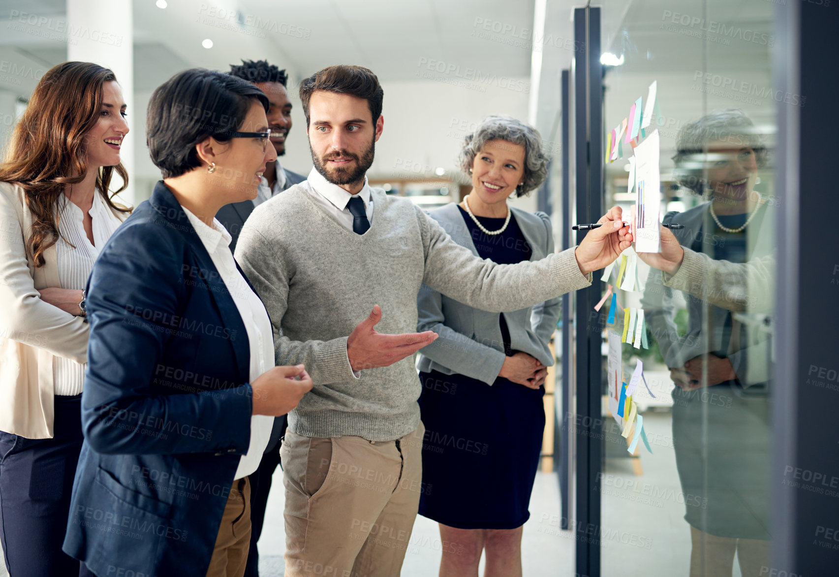 Buy stock photo Shot of a group of businesspeople brainstorming on a glass wall in an office